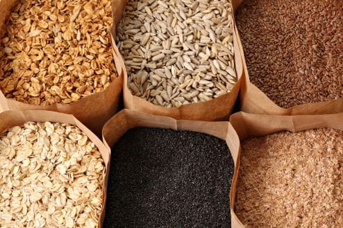 Six paper bags filled with different grains and cereals.